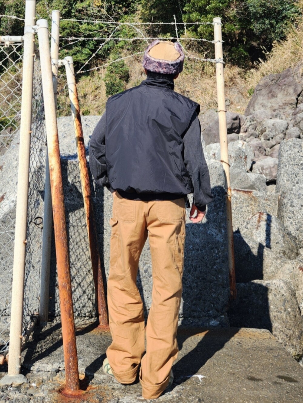 ブラック系のベスト、グレー系のスウェット、ブラウン系のパンツを着用したメンズの秋コーディネートの4枚目の写真