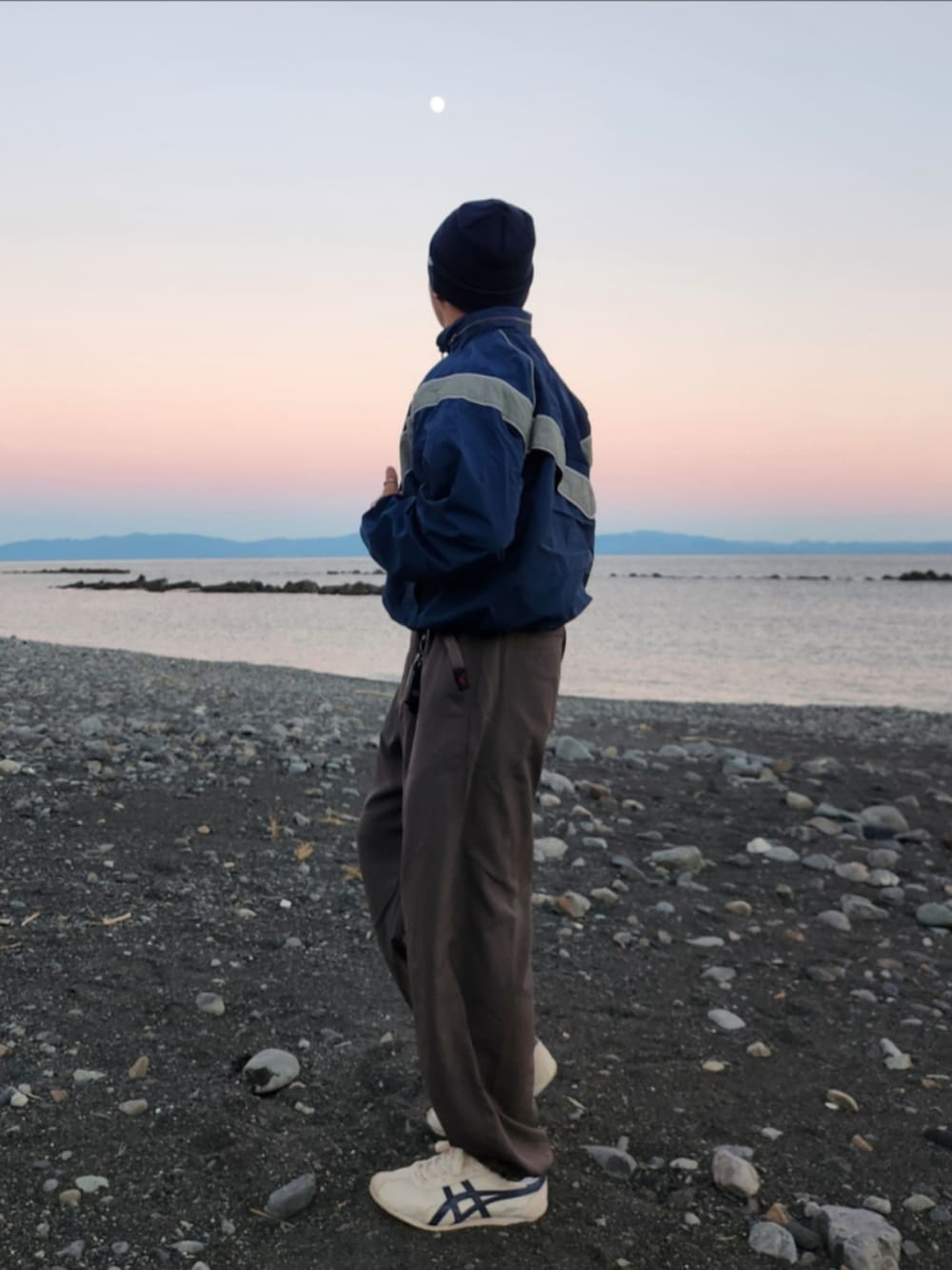 ブルー系のナイロンジャケット、グレー系のスラックス、ホワイト系のスニーカーを着用したメンズの秋コーディネートの4枚目の写真