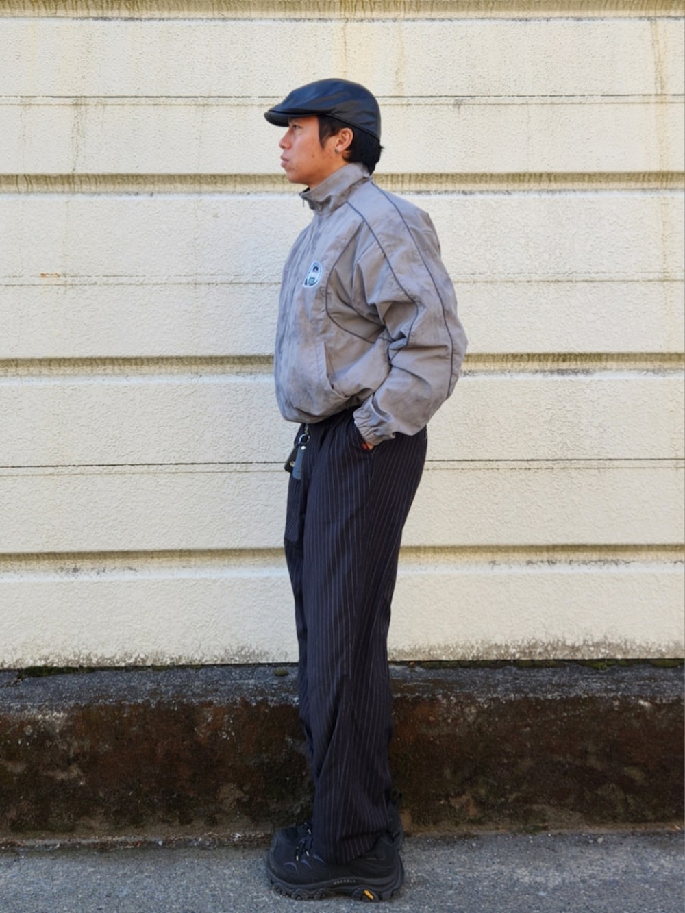 ブラック系のスラックス、ブラック系のスニーカー、シルバー系のナイロンジャケットを着用したメンズの冬コーディネートの2枚目の写真