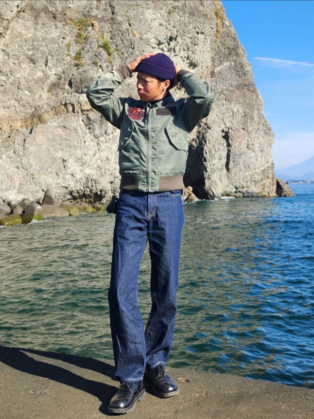 グリーン系のミリタリージャケット、ブラック系のその他トップス、ブルー系のデニムパンツを着用したメンズの秋コーディネートの2枚目の写真