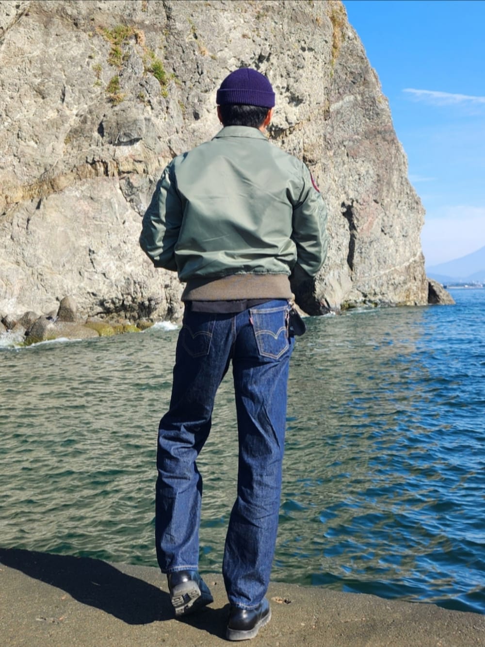 グリーン系のミリタリージャケット、ブラック系のその他トップス、ブルー系のデニムパンツを着用したメンズの秋コーディネートの4枚目の写真