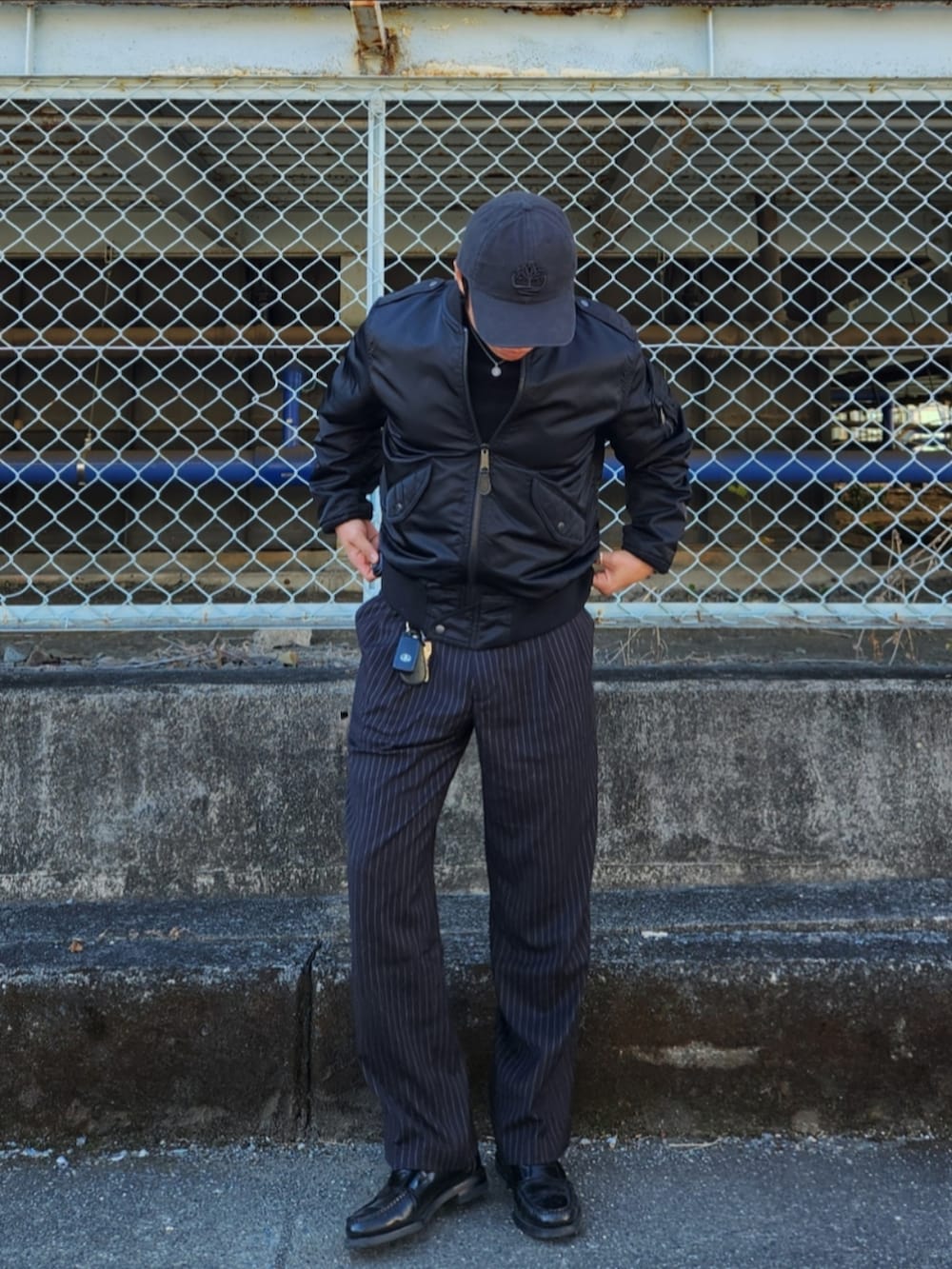 ブラック系のMA-1、ブラック系のスラックス、ブラック系のローファーを着用したメンズの冬コーディネートの2枚目の写真