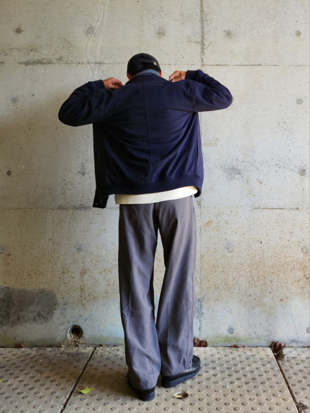 グレー系のスラックス、ブラック系のローファー、ホワイト系のスウェットを着用したメンズの秋コーディネートの4枚目の写真