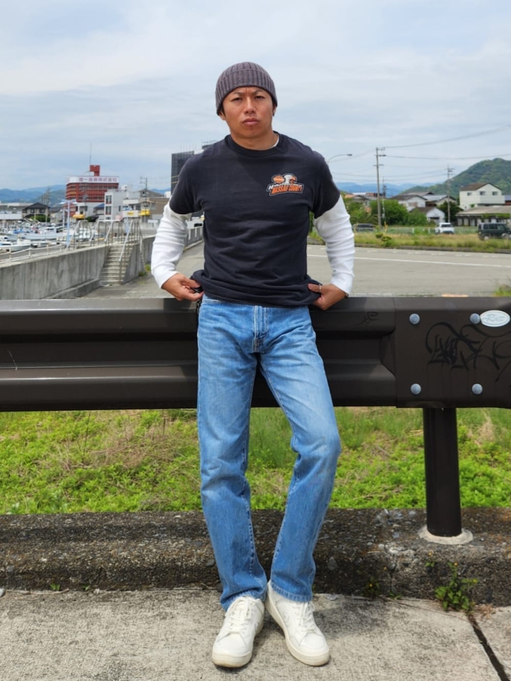 ブラック系のTシャツ/カットソー、ブルー系のデニムパンツ、ホワイト系のスニーカーを着用したメンズの春コーディネートの2枚目の写真