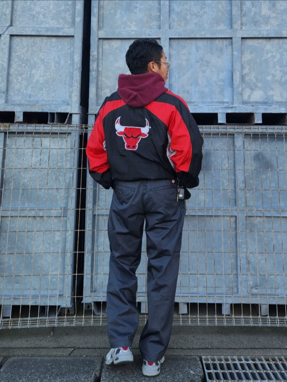 ブラック系のナイロンジャケット、レッド系のパーカー、グレー系のチノパンツを着用したメンズの秋コーディネートの5枚目の写真