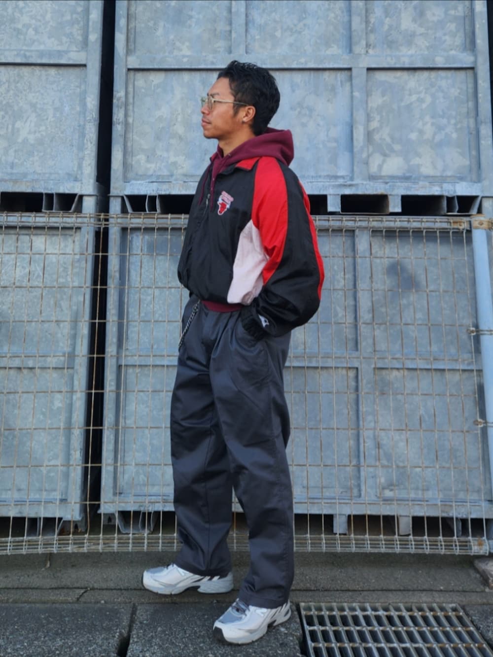 ブラック系のナイロンジャケット、レッド系のパーカー、グレー系のチノパンツを着用したメンズの秋コーディネートの4枚目の写真