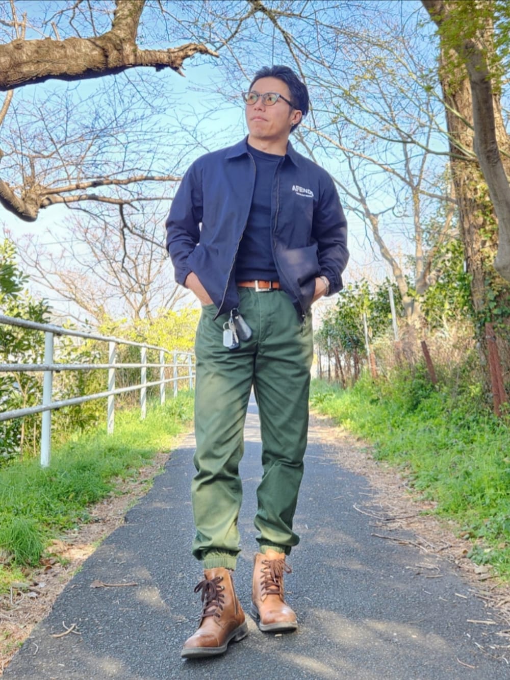 ブラウン系のブーツ、グリーン系のカーゴパンツ、ブラック系のTシャツ/カットソーを着用したメンズの春コーディネートの3枚目の写真