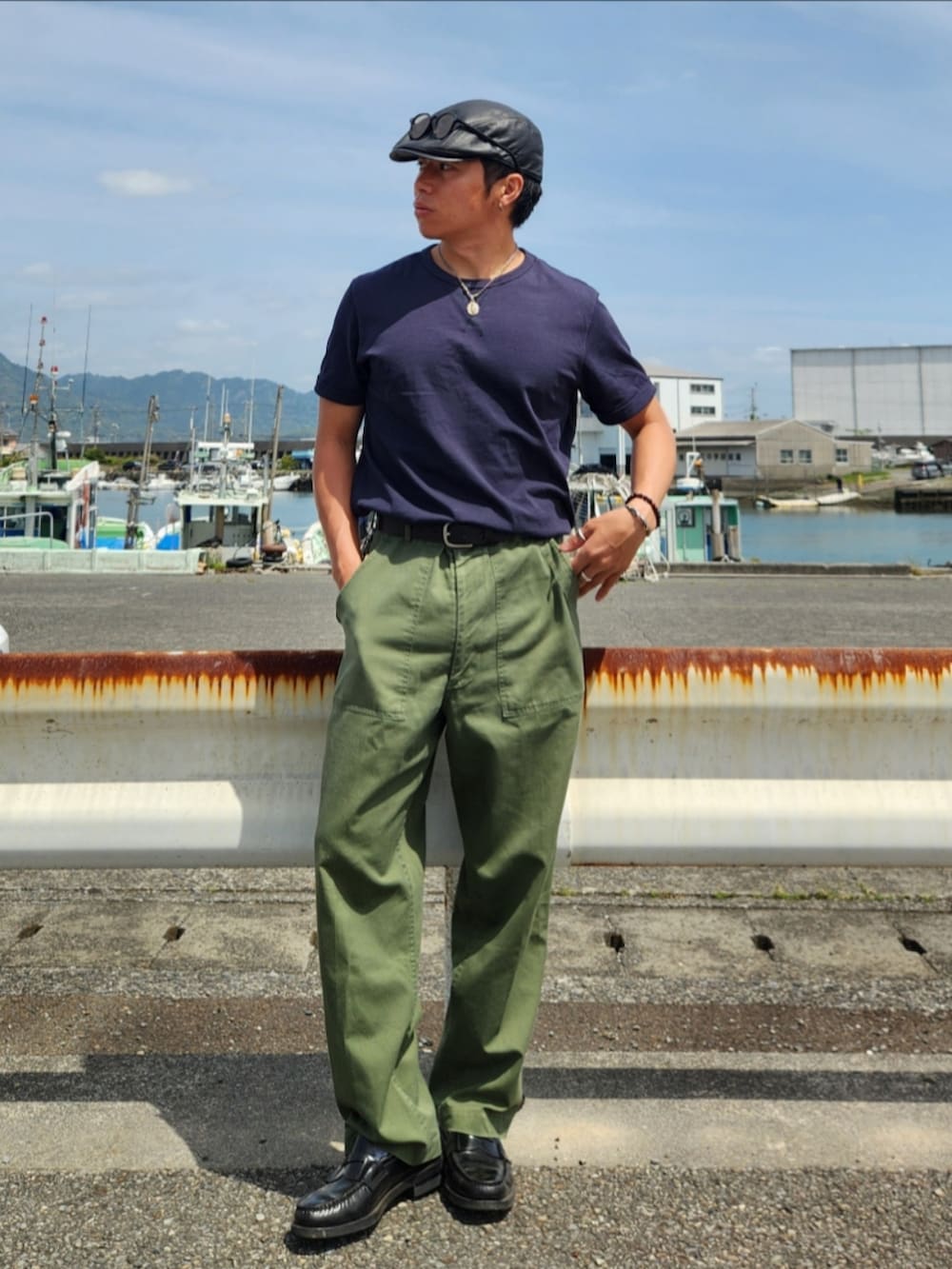 グリーン系のカーゴパンツ、ブラック系のローファー、ブラック系のTシャツ/カットソーを着用したメンズの春コーディネートの2枚目の写真