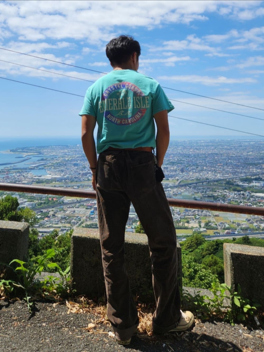 グリーン系のTシャツ/カットソー、ブラウン系のパンツ、ベージュ系のスニーカーを着用したメンズの春コーディネートの3枚目の写真