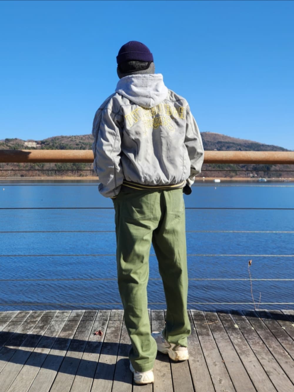 シルバー系のスタジャン、グレー系のパーカー、グリーン系のカーゴパンツを着用したメンズの秋コーディネートの3枚目の写真