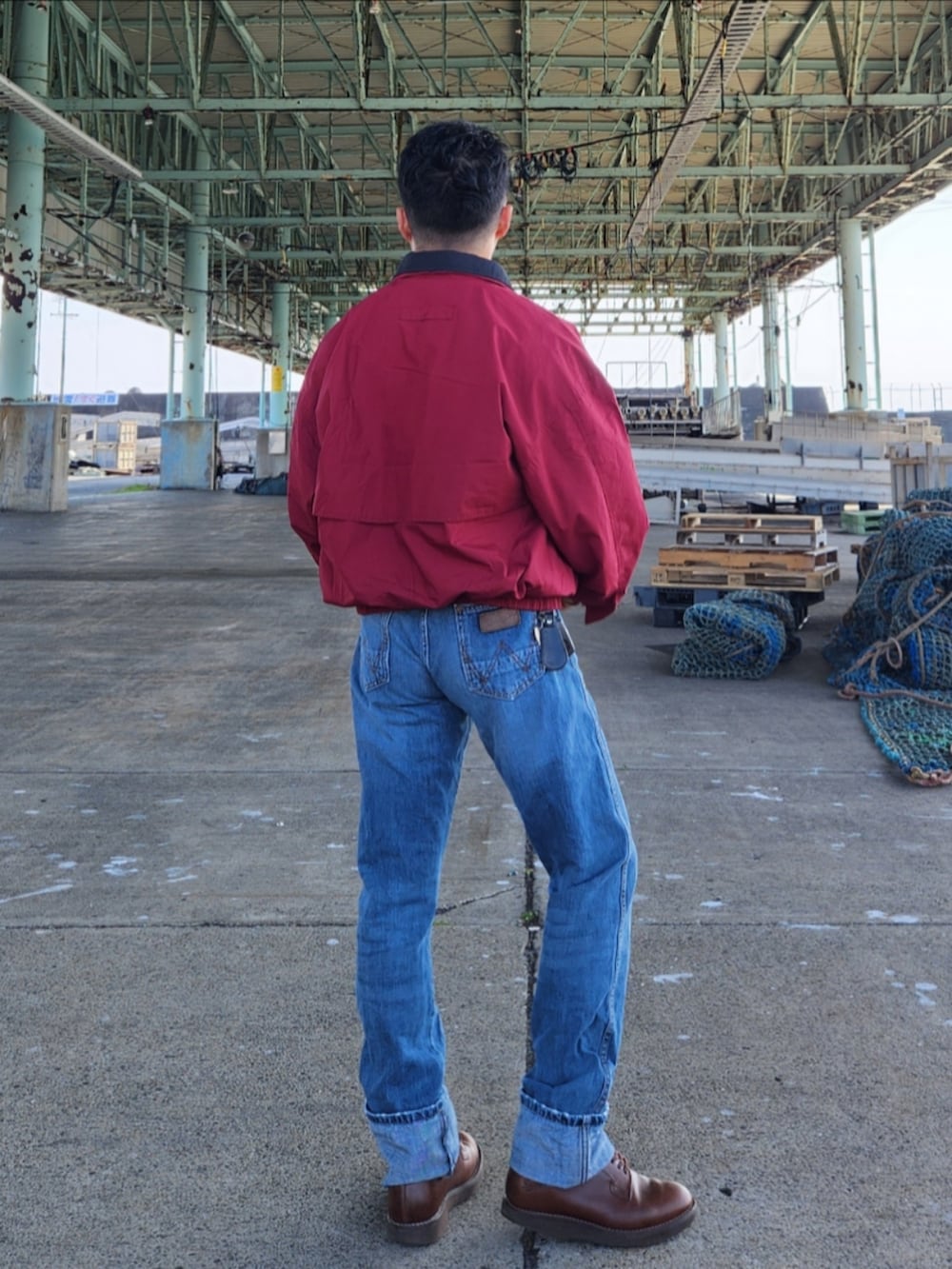 レッド系のナイロンジャケット、ブルー系のデニムパンツ、ブラウン系のブーツを着用したメンズの冬コーディネートの4枚目の写真