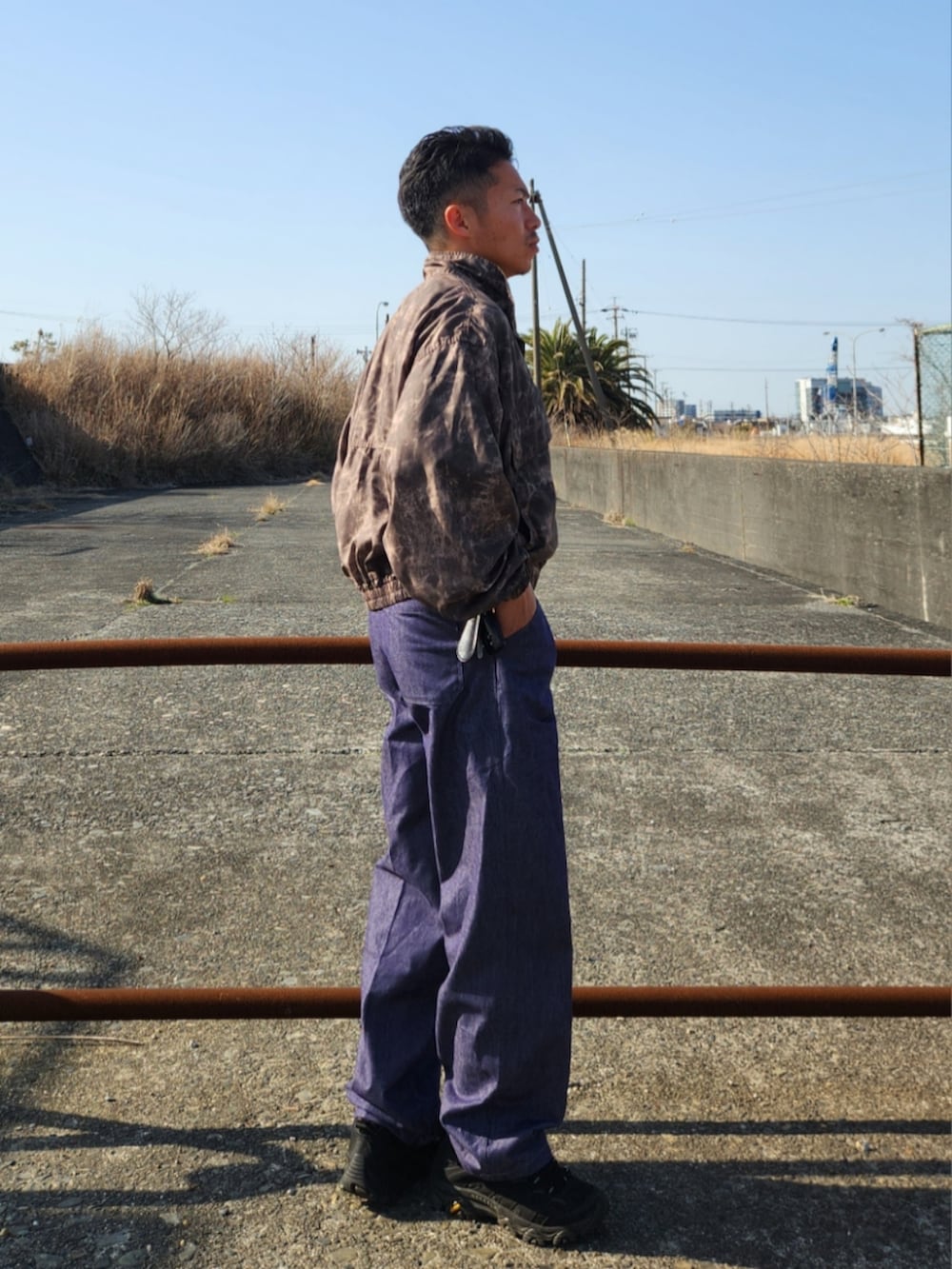 ブラウン系のナイロンジャケット、ブルー系のデニムパンツ、ブラック系のスニーカーを着用したメンズの春コーディネートの2枚目の写真