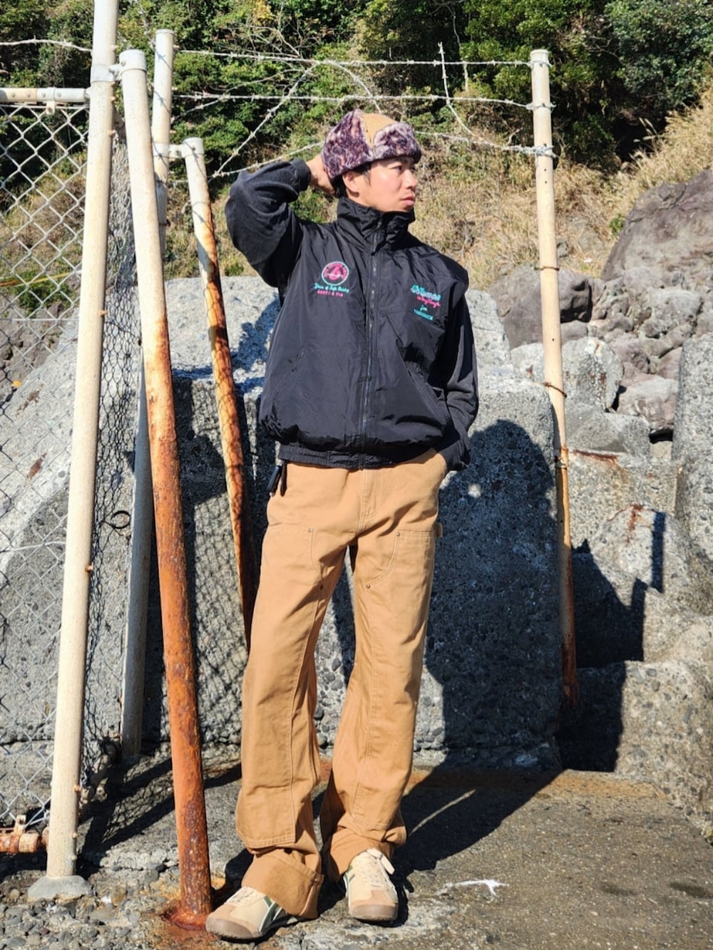 ブラック系のベスト、グレー系のスウェット、ブラウン系のパンツを着用したメンズの秋コーディネートの2枚目の写真