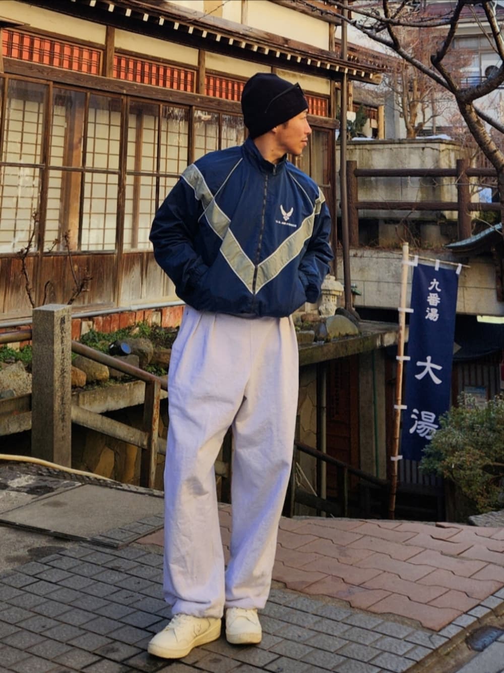 ブルー系のナイロンジャケット、グレー系のスウェットパンツ、ホワイト系のスニーカーを着用したメンズの冬コーディネートの2枚目の写真