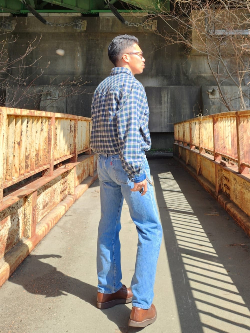 グリーン系のシャツ/ブラウス、ブルー系のデニムパンツ、ブラウン系のブーツを着用したメンズの春コーディネートの2枚目の写真