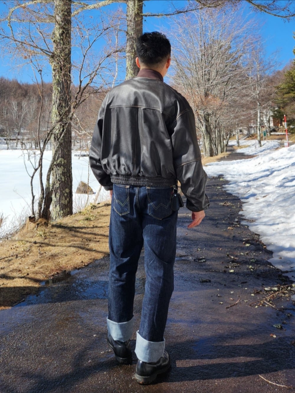 ブラウン系のブルゾン、ブルー系のデニムパンツ、ブラック系のブーツを着用したメンズの冬コーディネートの4枚目の写真