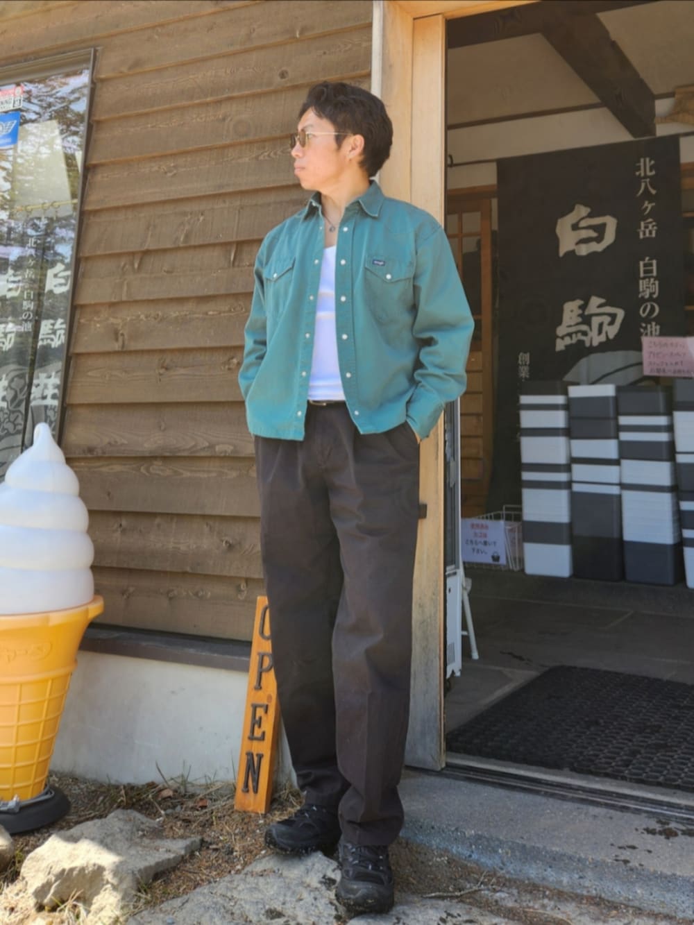 グリーン系のデニムジャケット、ブラック系のスラックス、ブラック系のスニーカーを着用したメンズの春コーディネートの2枚目の写真