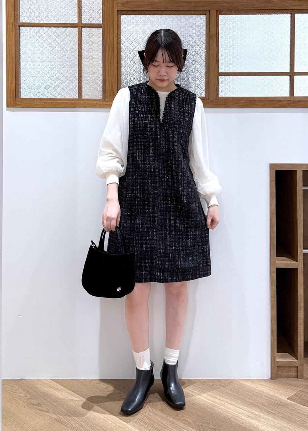 ブラック系のワンピース、ホワイト系のニット/セーター、ブラック系のブーツを着用したレディースの秋コーディネートの9枚目の写真