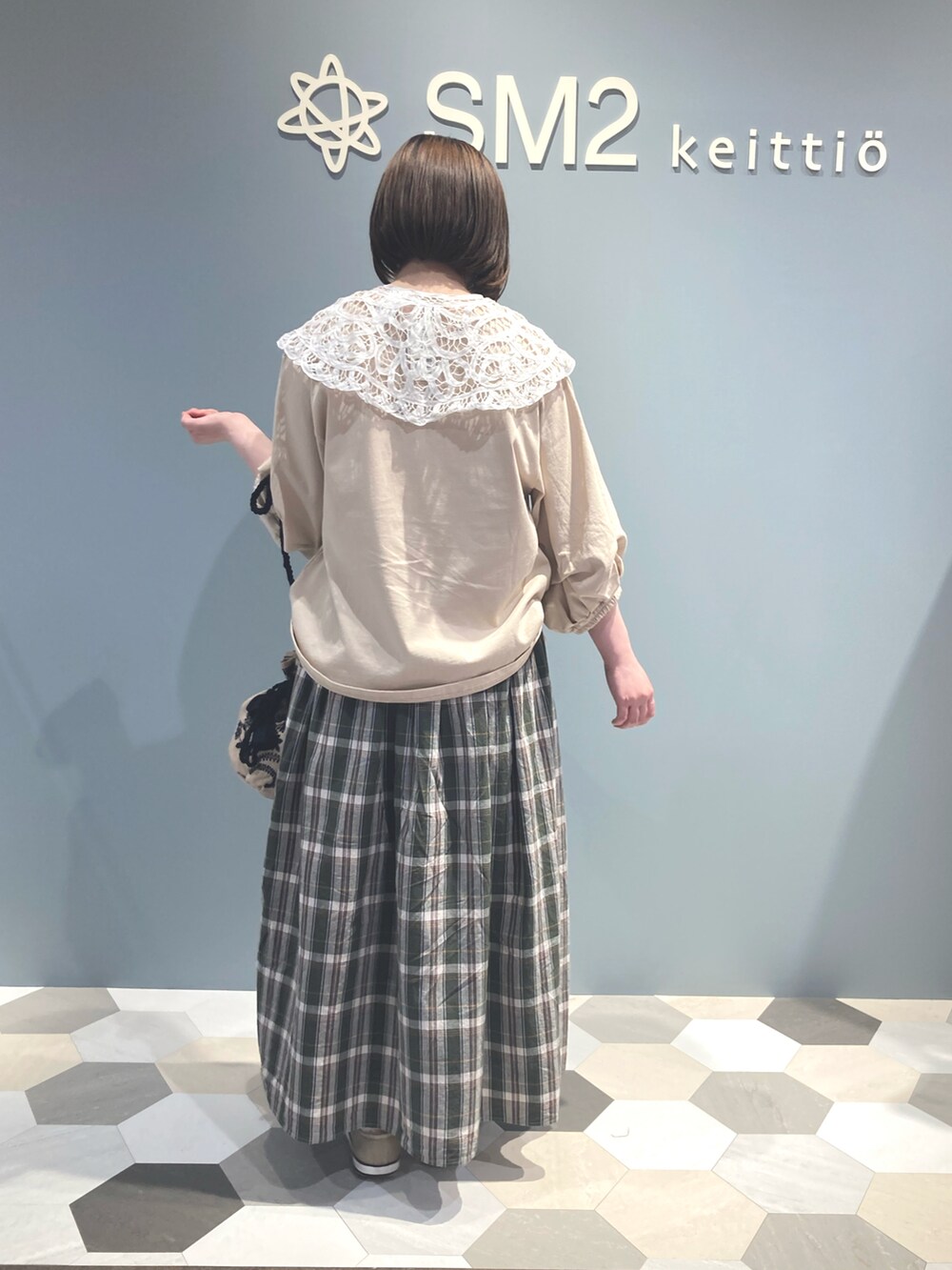 グリーン系のスカート、ベージュ系のハンドバッグ、ベージュ系のTシャツ/カットソーを着用したレディースの春コーディネートの2枚目の写真