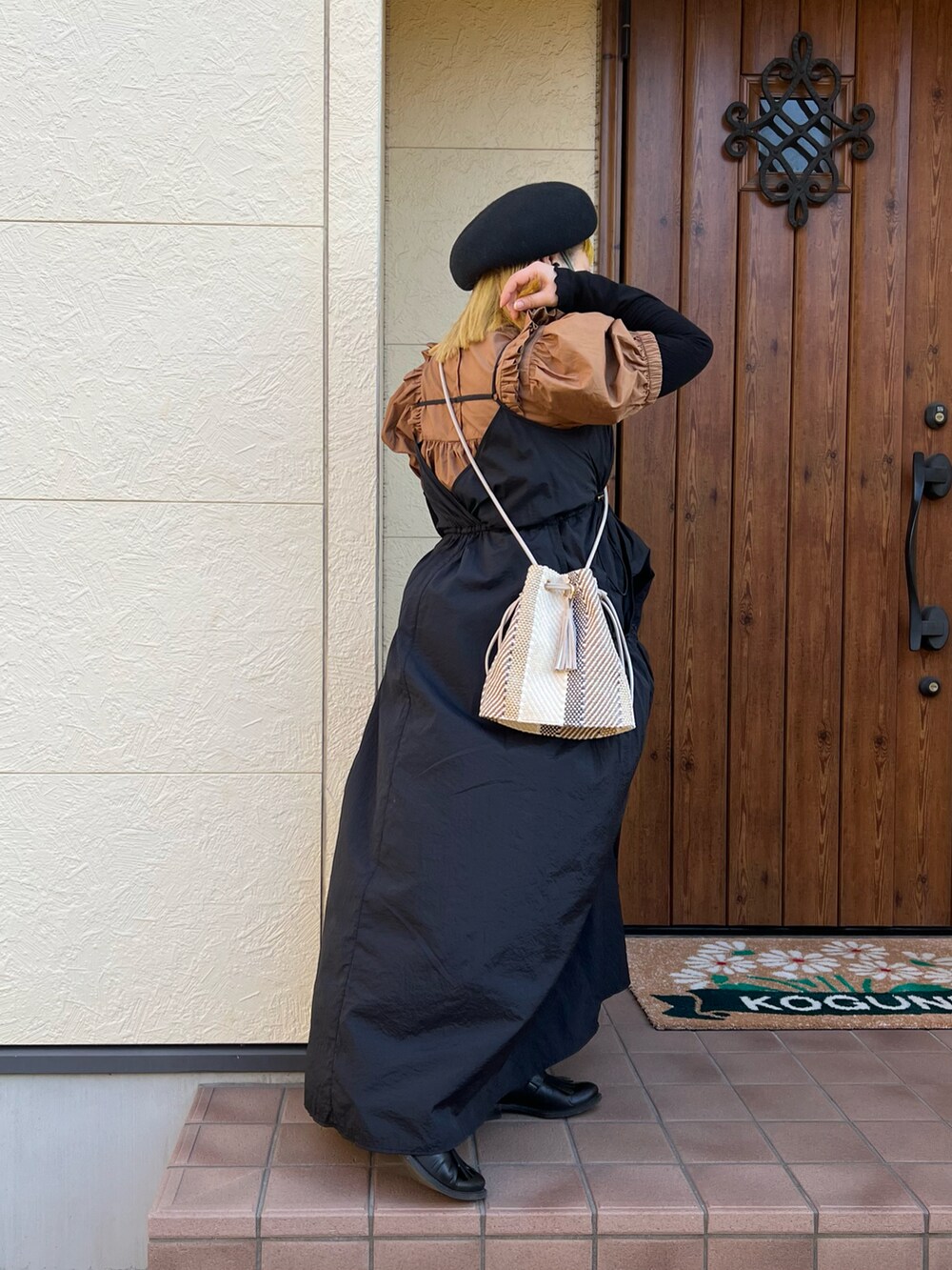 ベージュ系のショルダーバッグ、ブラック系のワンピース、ブラウン系のシャツ/ブラウスを着用したレディースの冬コーディネートの2枚目の写真