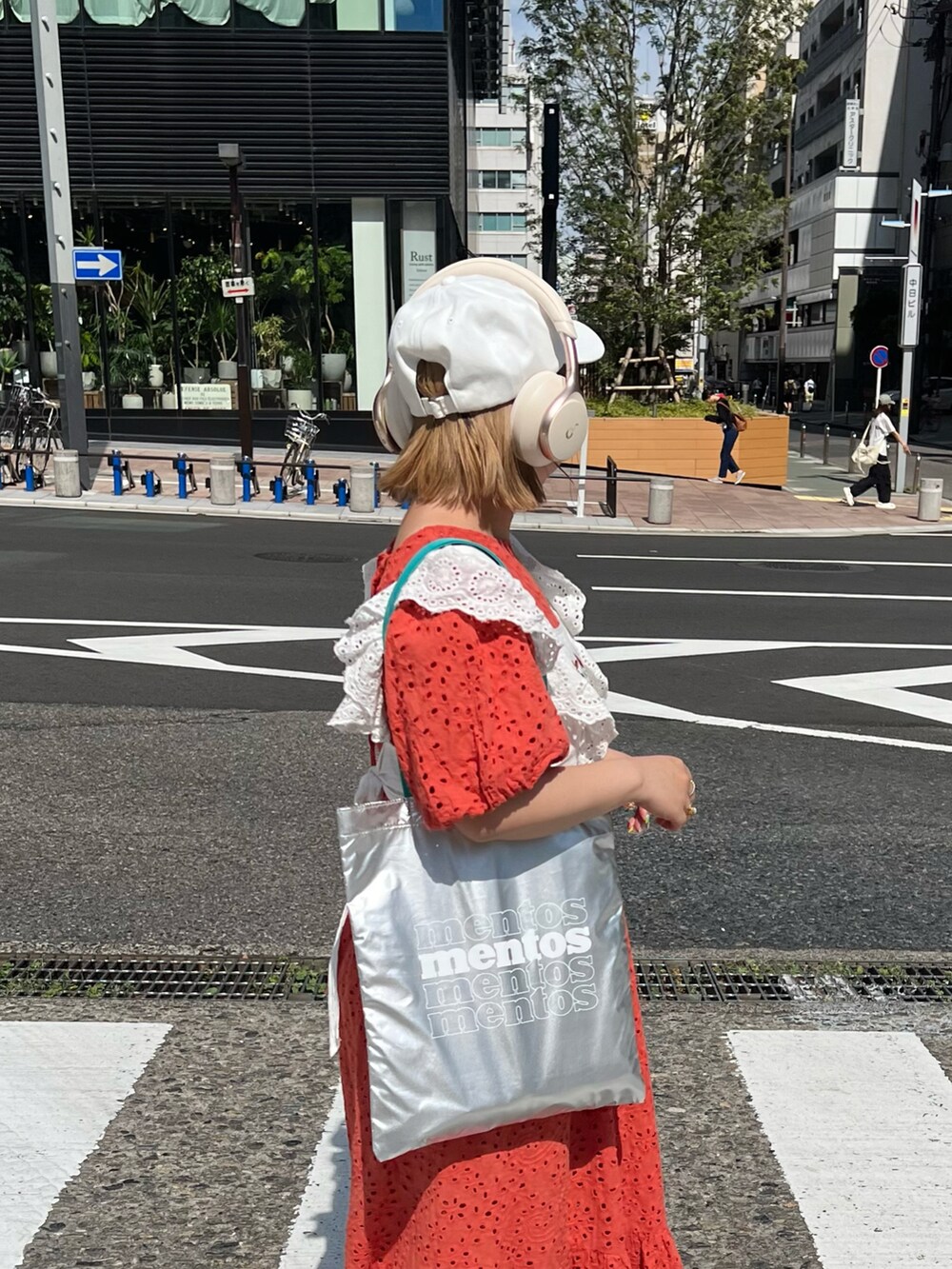 シルバー系のトートバッグ、オレンジ系のワンピース、ホワイト系のスニーカーを着用したレディースの夏コーディネートの2枚目の写真