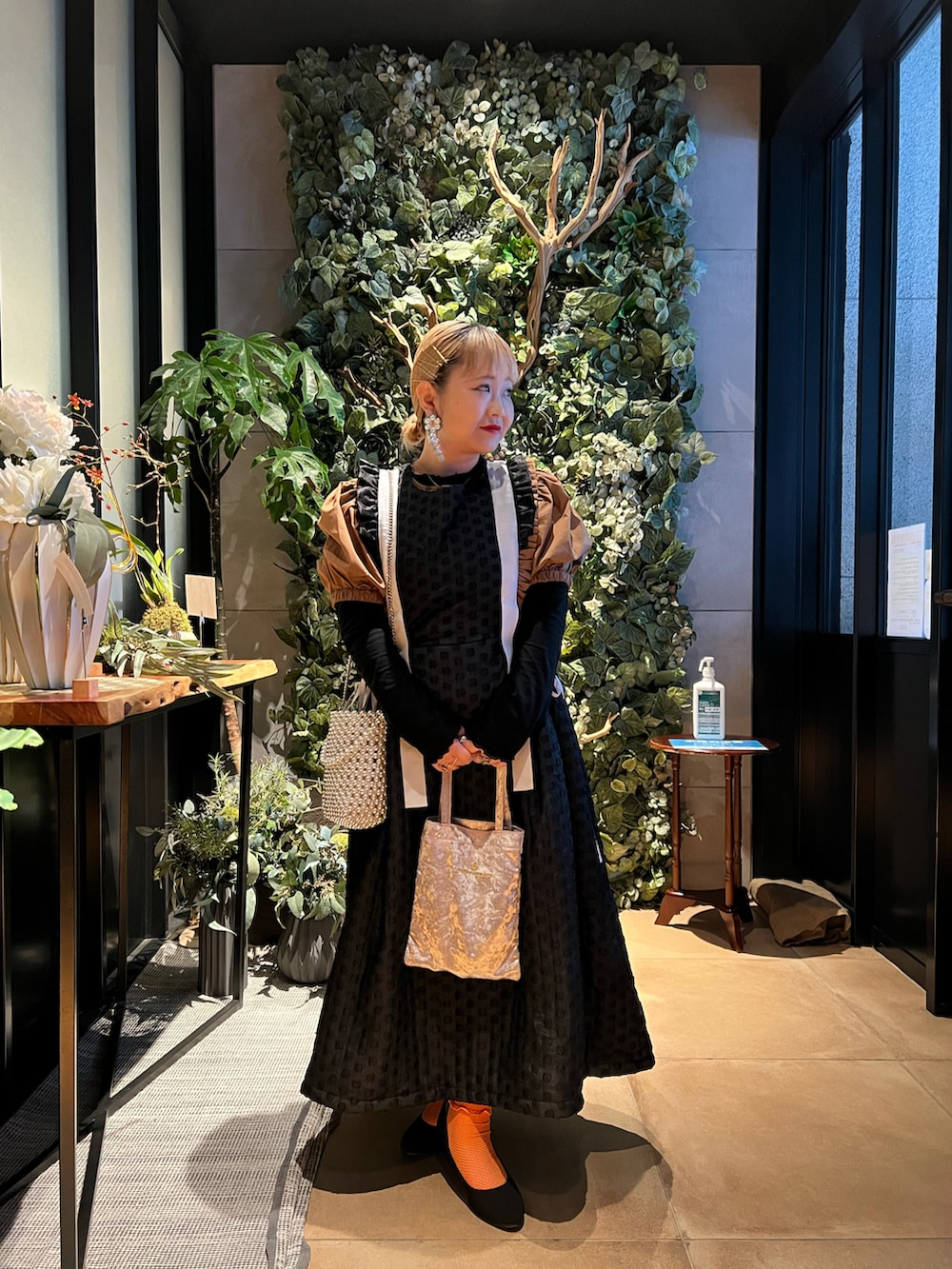 ベージュ系のハンドバッグ、ブラック系のワンピース、ホワイト系のショルダーバッグを着用したレディースの冬コーディネートの2枚目の写真