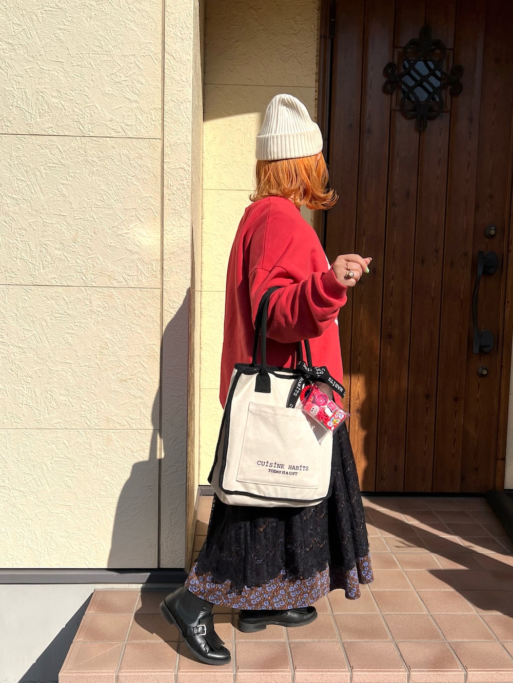 ホワイト系のトートバッグ、レッド系のスウェット、ブラウン系のワンピースを着用したレディースの冬コーディネートの2枚目の写真