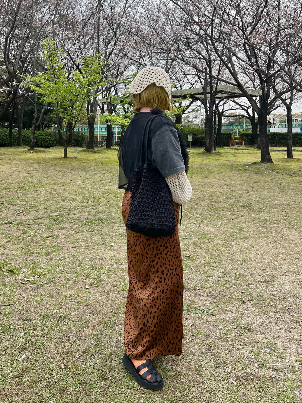 ブラック系のトートバッグ、ブラック系のTシャツ/カットソー、ホワイト系のニット/セーターを着用したレディースの春コーディネートの2枚目の写真