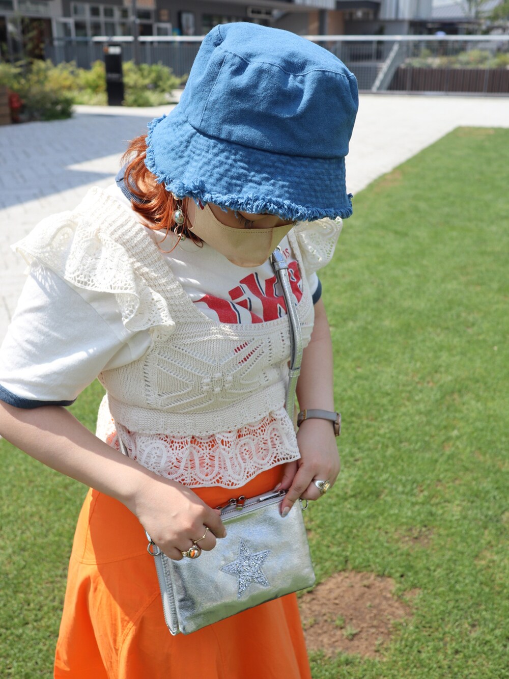 オレンジ系のスカート、ホワイト系のサンダル、ホワイト系のトップスを着用したレディースの夏コーディネートの2枚目の写真