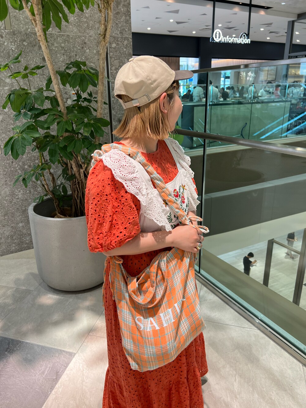 オレンジ系のトートバッグ、オレンジ系のワンピース、ホワイト系のスニーカーを着用したレディースの秋コーディネートの2枚目の写真