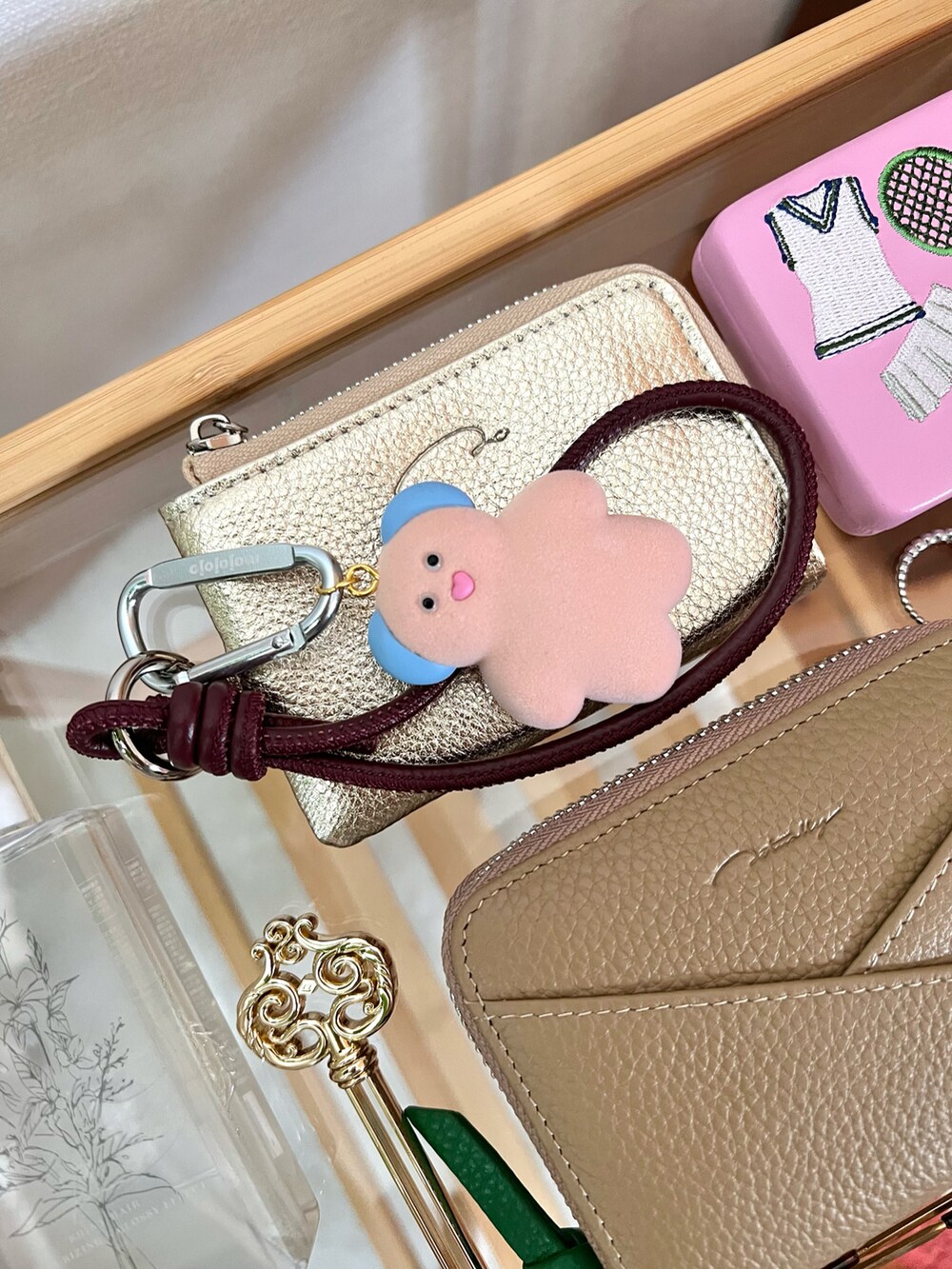 ベージュ系の財布、ゴールド系の財布、ピンク系のその他小物を着用したレディースの秋コーディネートの2枚目の写真