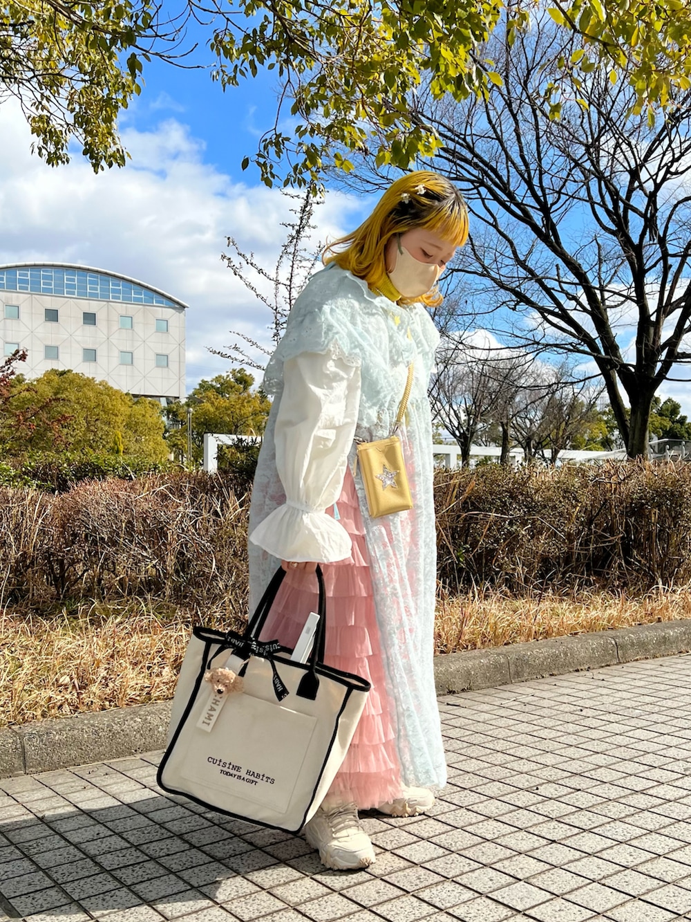 ホワイト系のトートバッグ、ホワイト系のカーディガン/ボレロ、イエロー系のニット/セーターを着用したレディースの冬コーディネートの2枚目の写真