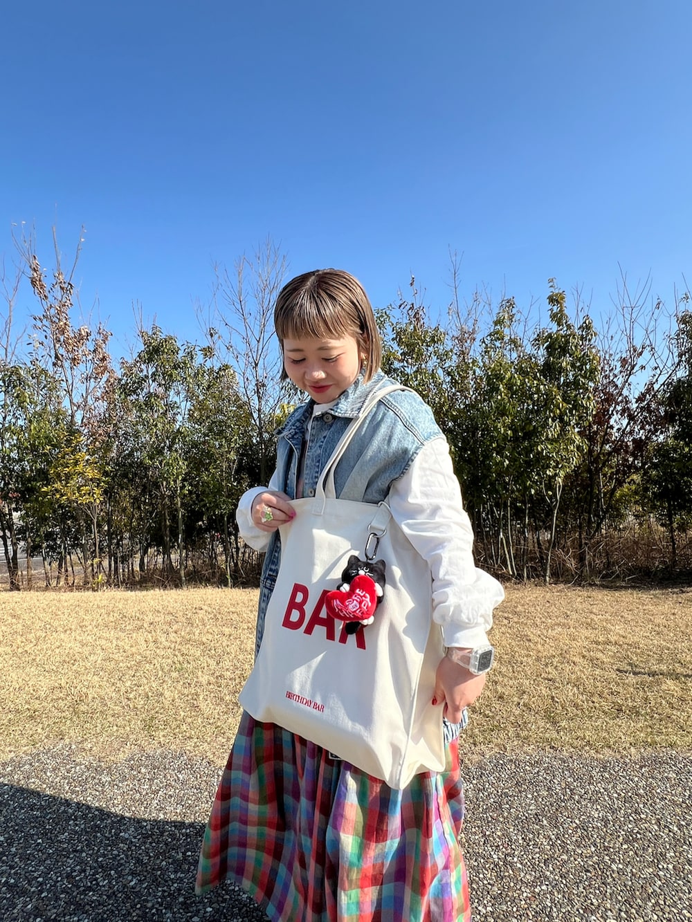 ホワイト系のトートバッグ、ブラック系のチャーム、その他のその他を着用したレディースの春コーディネートの2枚目の写真