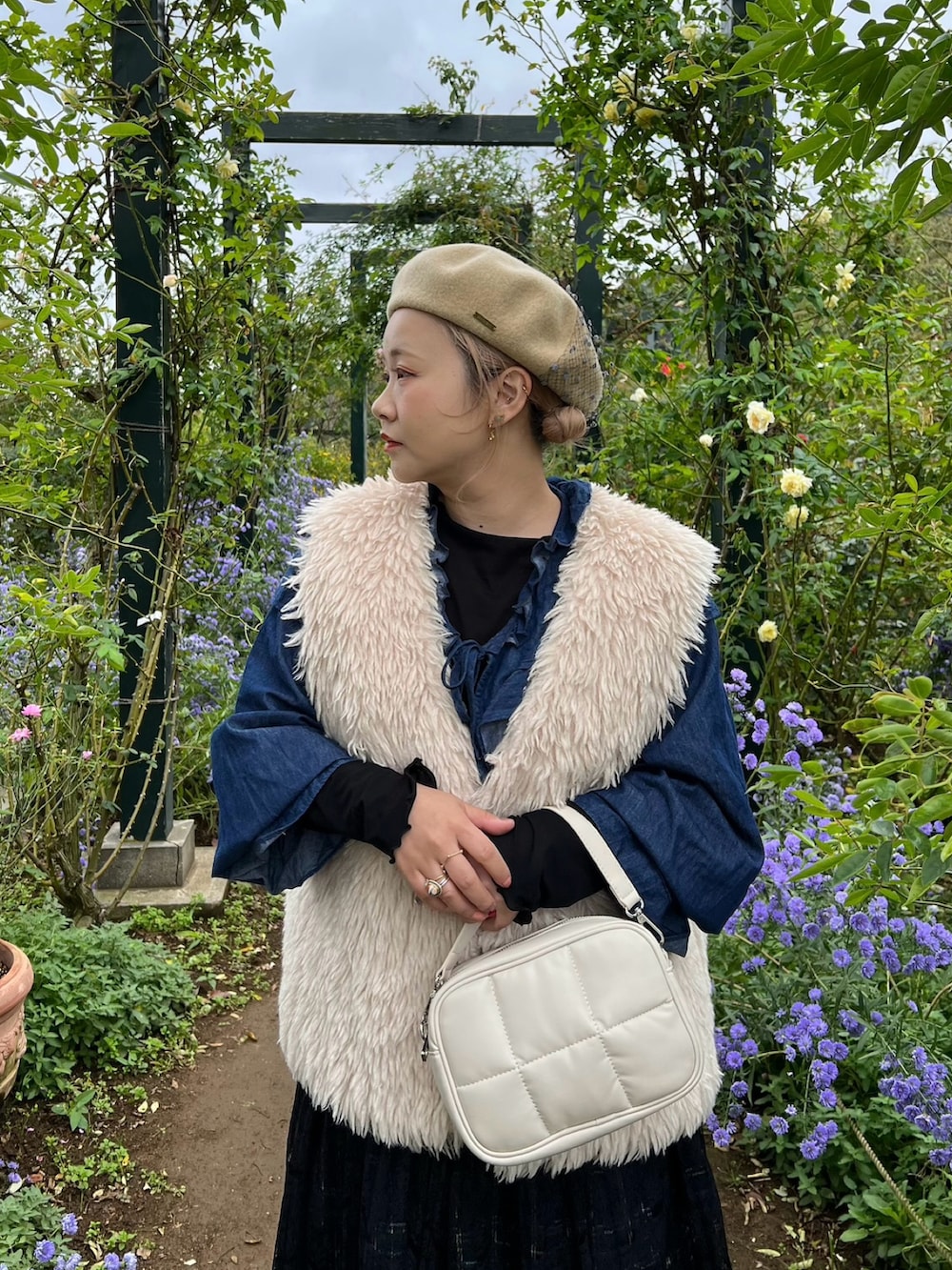 ホワイト系のショルダーバッグ、ベージュ系のベスト、ブルー系のカーディガン/ボレロを着用したレディースの冬コーディネートの2枚目の写真