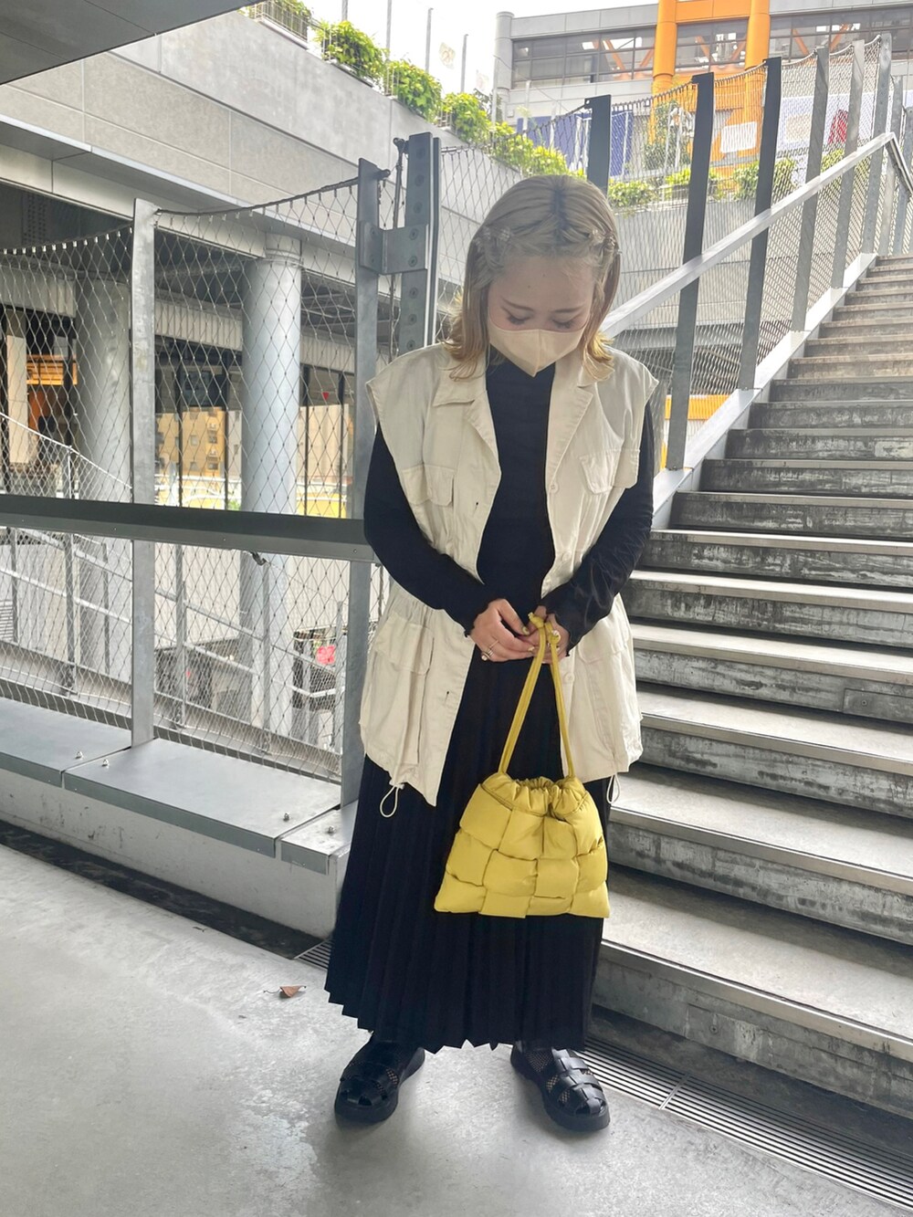 イエロー系のショルダーバッグ、ブラック系のスカート、ホワイト系のベストを着用したレディースの秋コーディネートの3枚目の写真