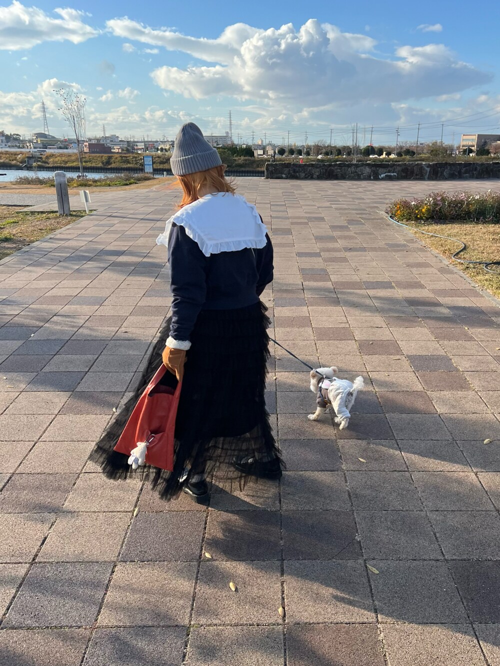 オレンジ系のトートバッグ、ホワイト系のシャツ/ブラウス、ブルー系のスウェットを着用したレディースの冬コーディネートの2枚目の写真