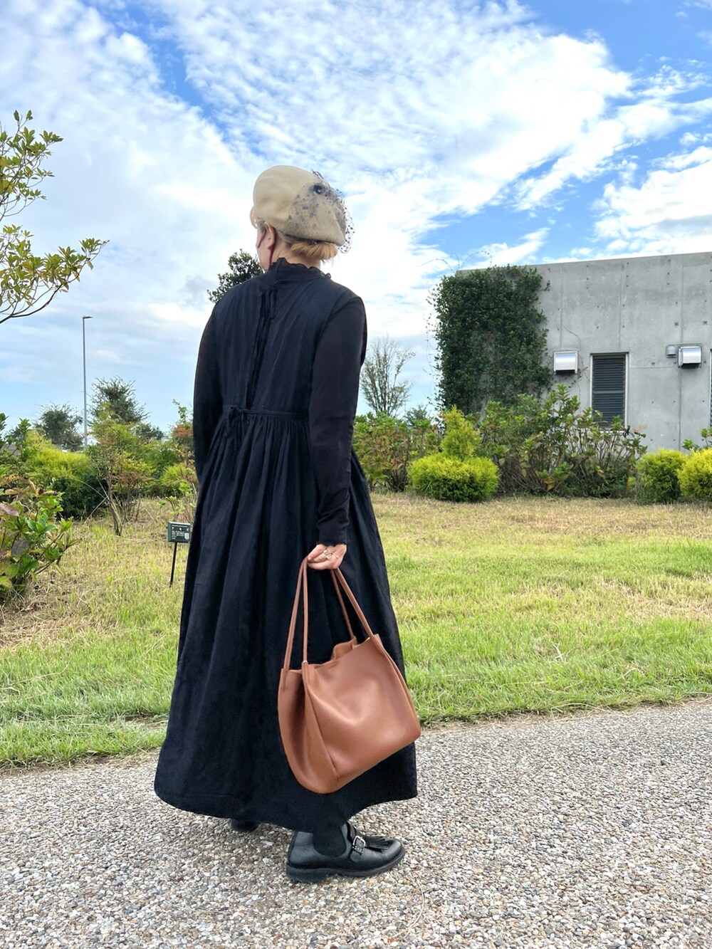 ブラウン系のトートバッグ、ブラック系のワンピース、ブラック系のブーツを着用したレディースの秋コーディネートの3枚目の写真