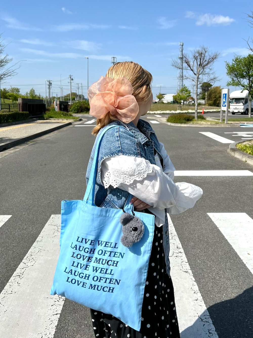 ブルー系のトートバッグ、ブルー系のジャケット/アウター、ブラック系のワンピースを着用したレディースの夏コーディネートの2枚目の写真