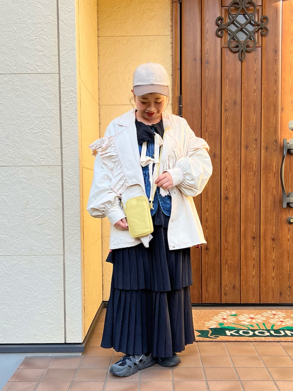 イエロー系のショルダーバッグ、ホワイト系のテーラードジャケット、ブラック系のTシャツ/カットソーを着用したレディースの冬コーディネートの2枚目の写真