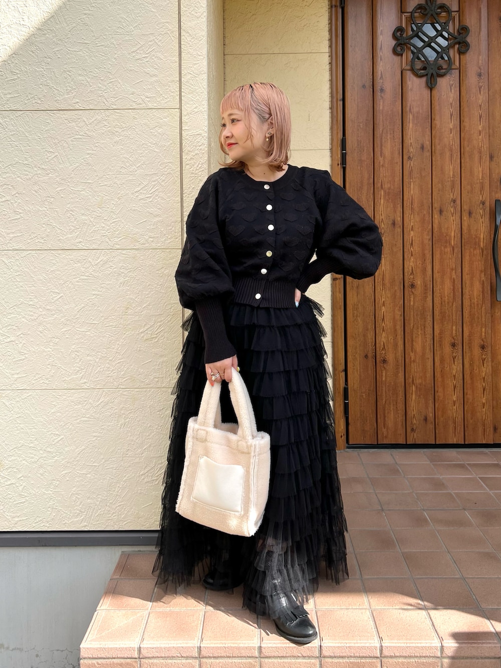 ホワイト系のトートバッグ、ブラック系のニット/セーター、ブラック系のスカートを着用したレディースの秋コーディネートの2枚目の写真