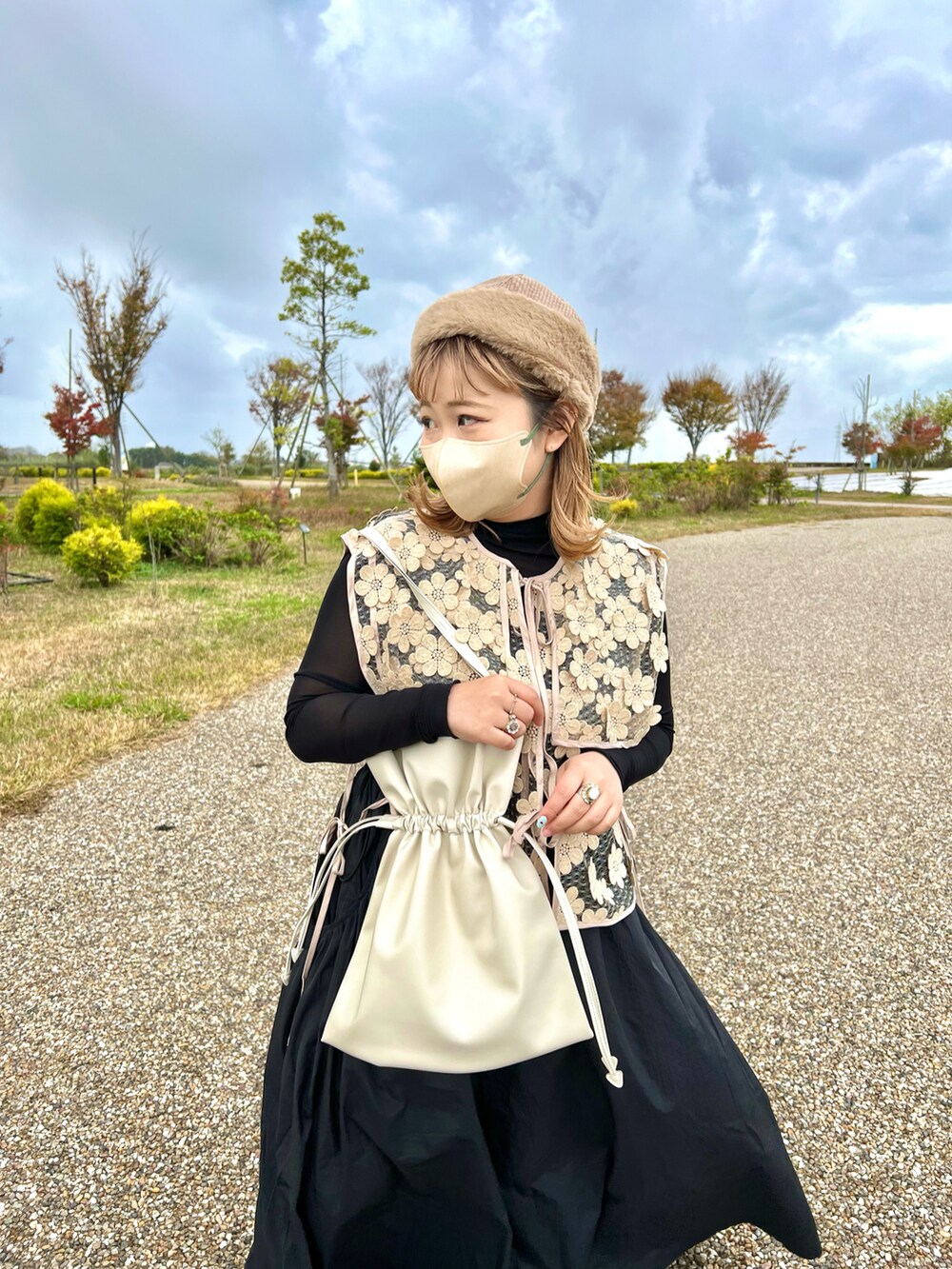 ホワイト系のトートバッグ、ブラック系のワンピース、ベージュ系のベストを着用したレディースの冬コーディネートの2枚目の写真