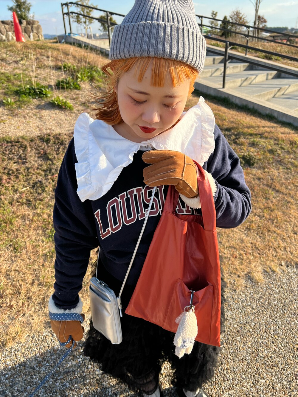 オレンジ系のトートバッグ、ホワイト系のシャツ/ブラウス、ブルー系のスウェットを着用したレディースの冬コーディネートの3枚目の写真