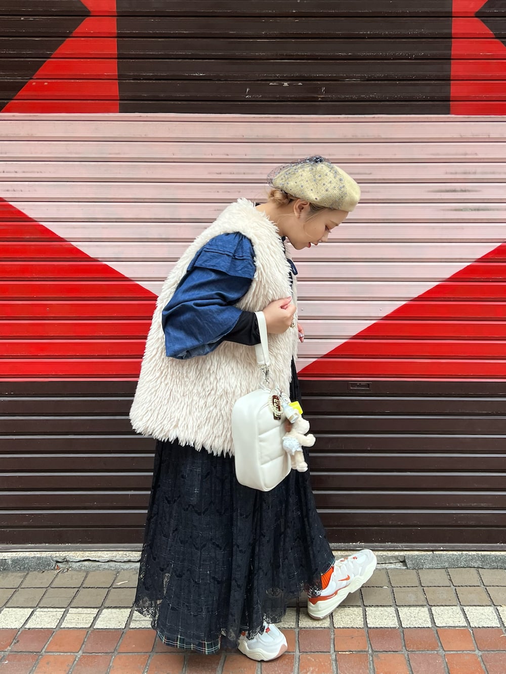 ホワイト系のショルダーバッグ、ベージュ系のベスト、ブルー系のカーディガン/ボレロを着用したレディースの冬コーディネートの3枚目の写真