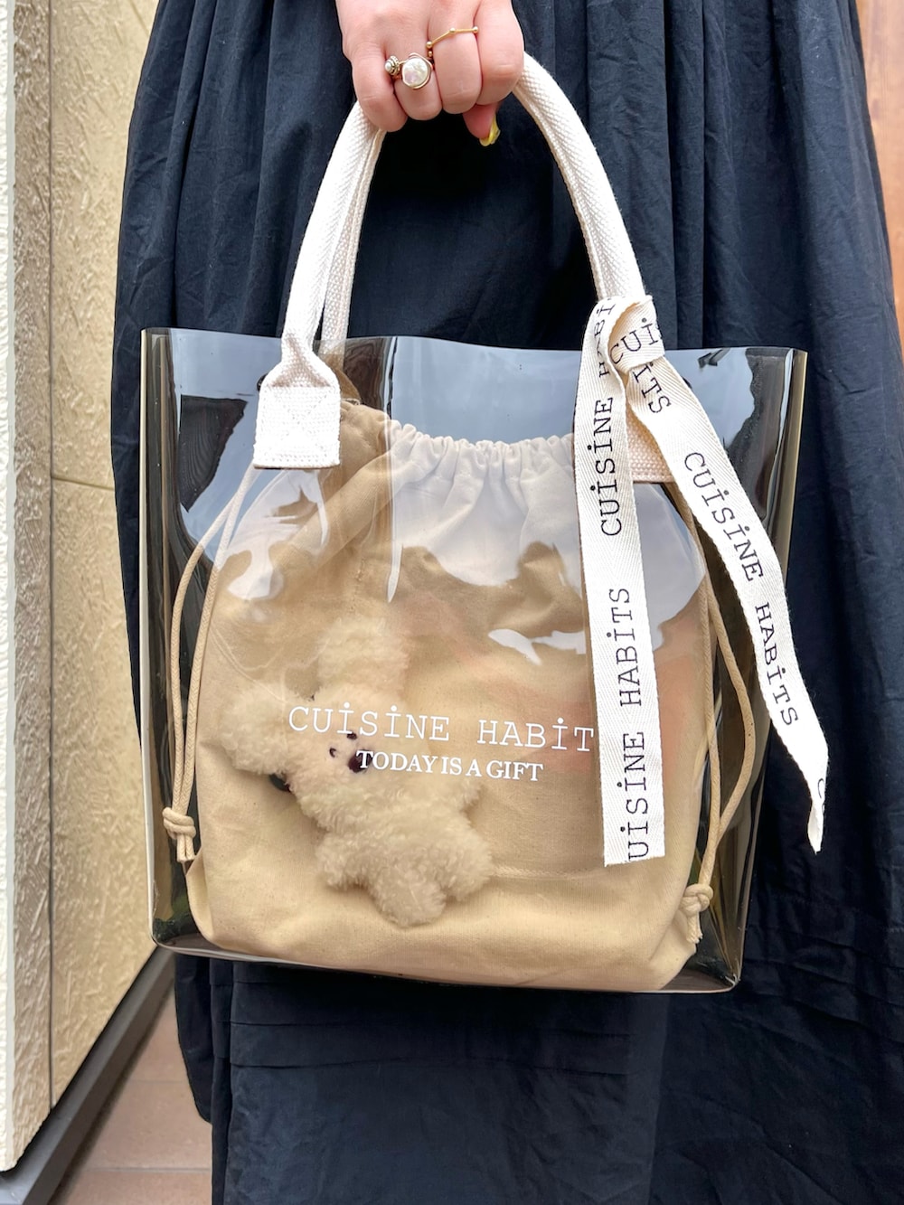 ホワイト系のトートバッグ、ブラック系のワンピース、ホワイト系のサンダルを着用したレディースの夏コーディネートの3枚目の写真