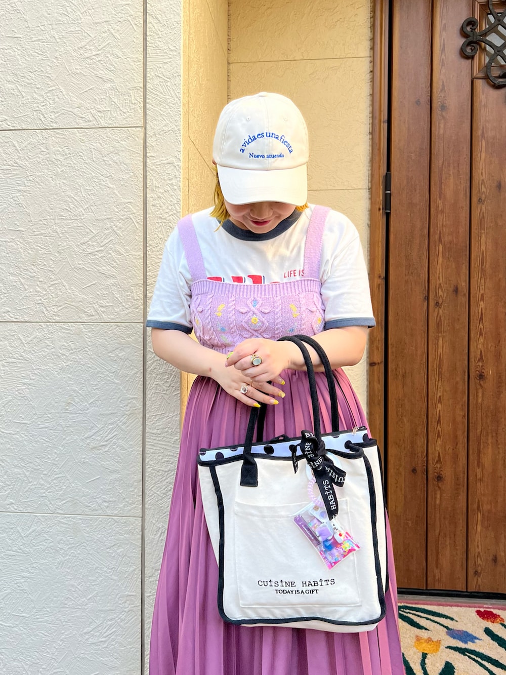 ホワイト系のトートバッグ、ホワイト系のスニーカー、ホワイト系のキャップを着用したレディースの夏コーディネートの2枚目の写真