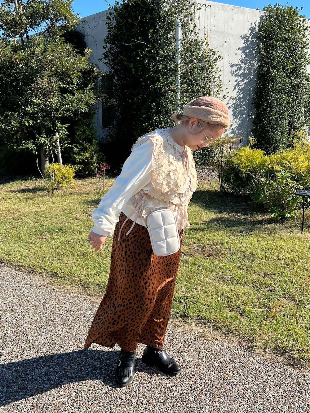 ホワイト系のショルダーバッグ、ベージュ系のベスト、ホワイト系のスウェットを着用したレディースの秋コーディネートの2枚目の写真