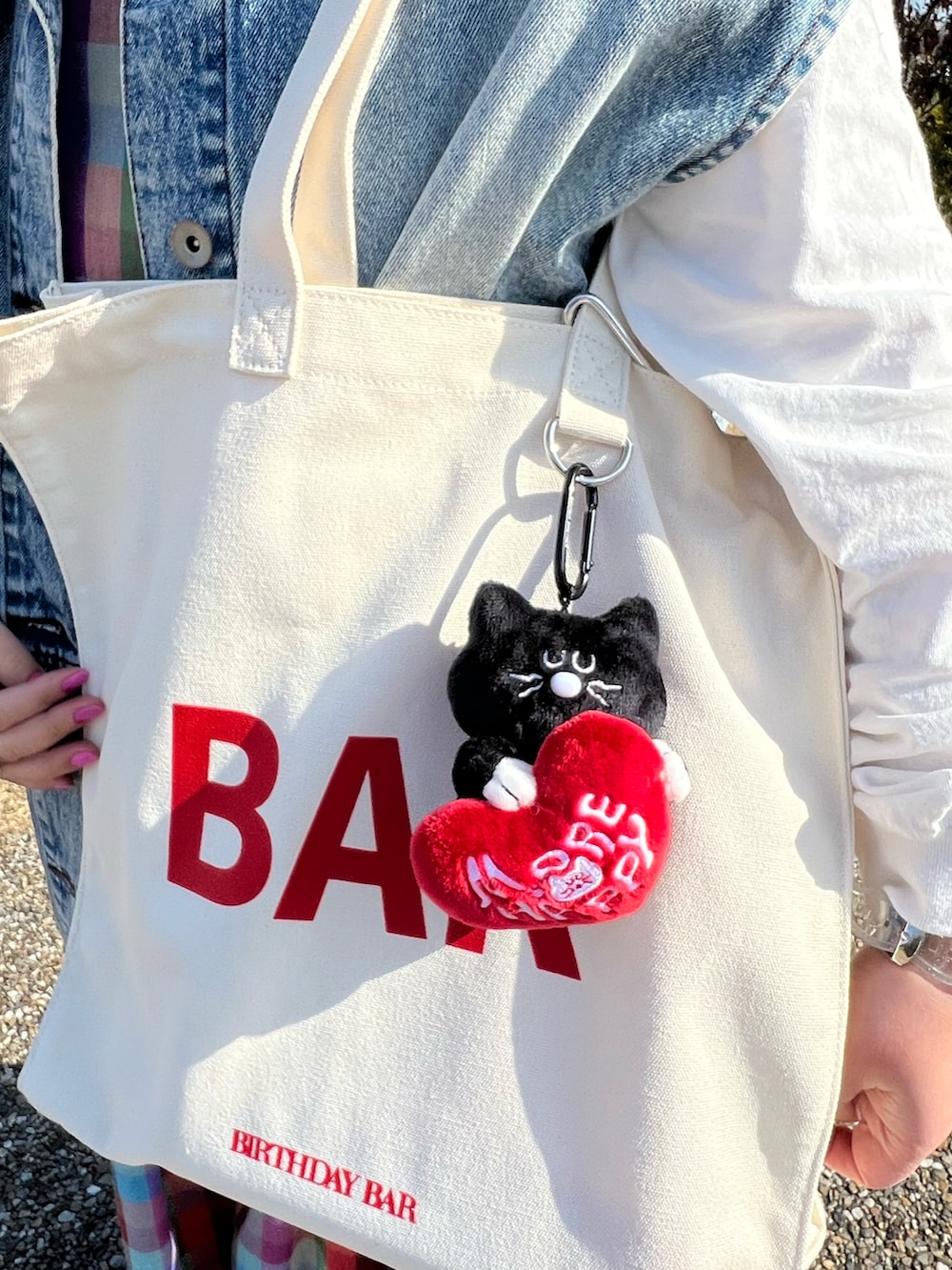 ブラック系のチャーム、ブラック系のスマホグッズ、ピンク系のポーチを着用したレディースの春コーディネートの4枚目の写真