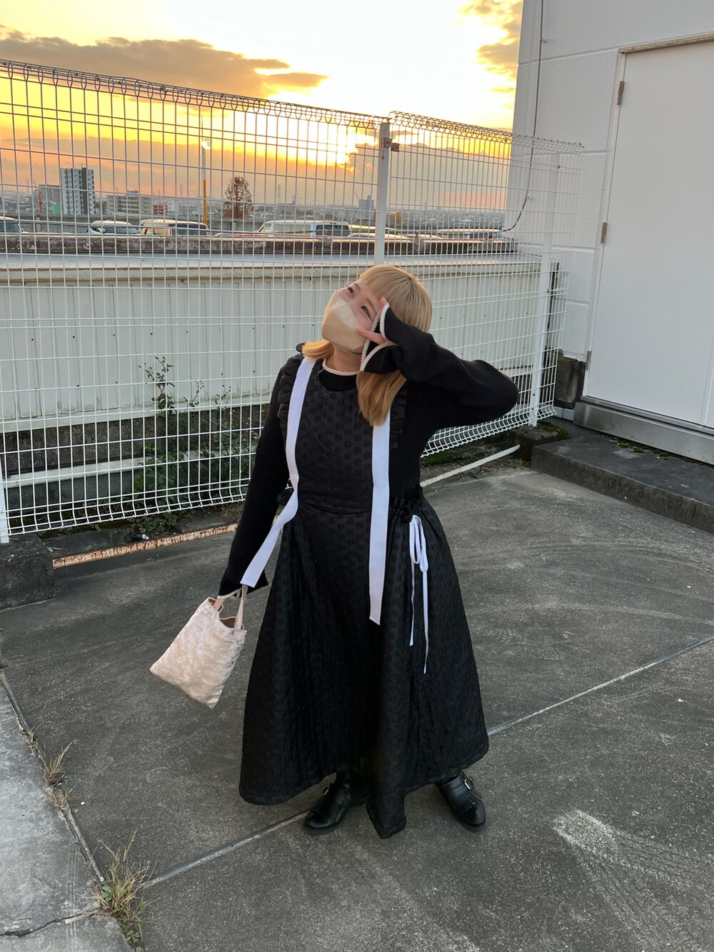 ホワイト系のダウンジャケット/コート、ベージュ系のハンドバッグ、ブラック系のワンピースを着用したレディースの冬コーディネートの3枚目の写真