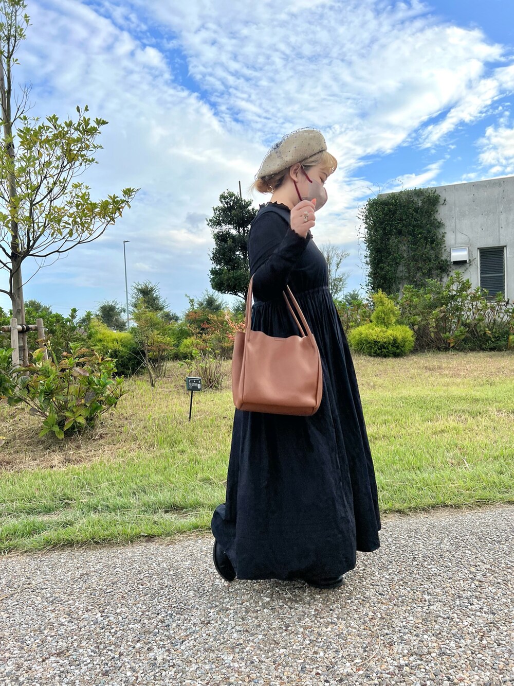 ブラウン系のトートバッグ、ブラック系のワンピース、ブラック系のブーツを着用したレディースの秋コーディネートの2枚目の写真