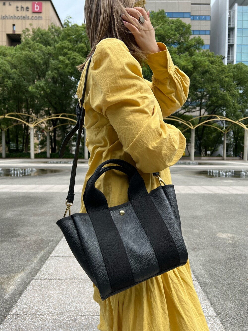 ブラック系のトートバッグ、イエロー系のワンピースを着用したレディースの秋コーディネートの4枚目の写真
